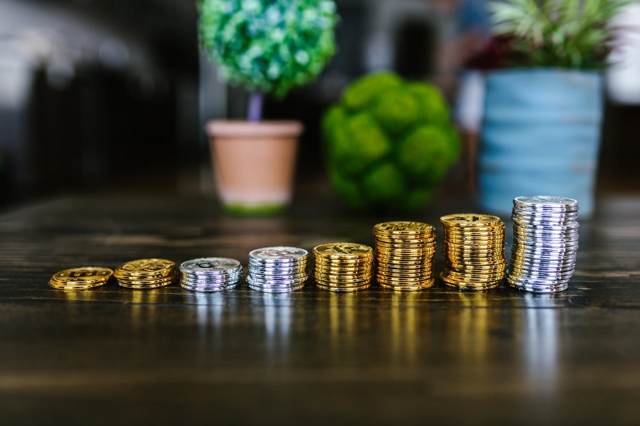 Close-up of stacked gold and silver bitcoins on a wooden table with plants in the background.